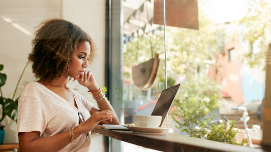 black woman natural hair nourished moisturized lips reading on laptop with coffee in cozy clothes and environment resting deep or deeply